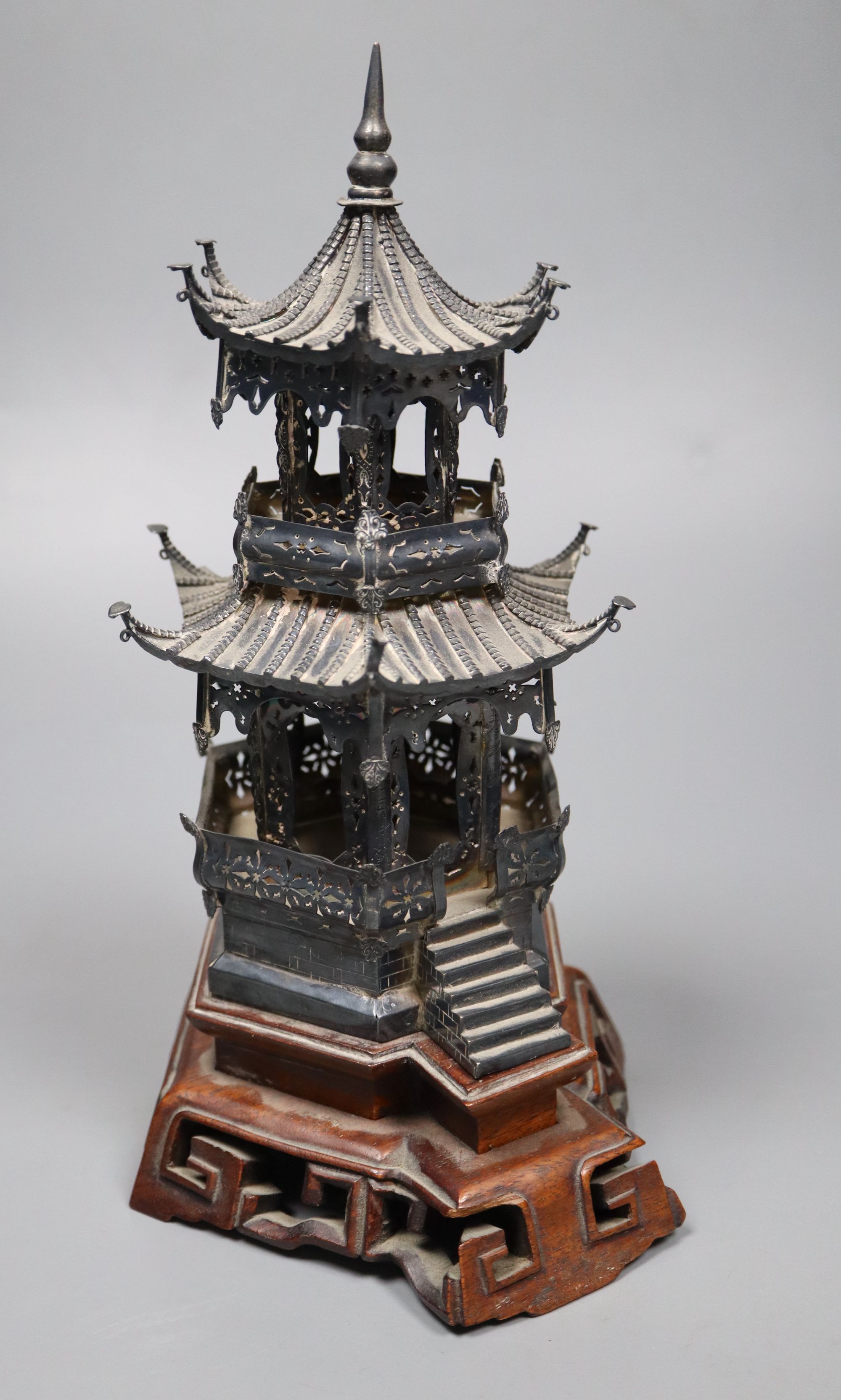 An early 20th century Chinese white metal miniature model of a pagoda, on a hardwood base, model 21.4cm, 11.5oz,